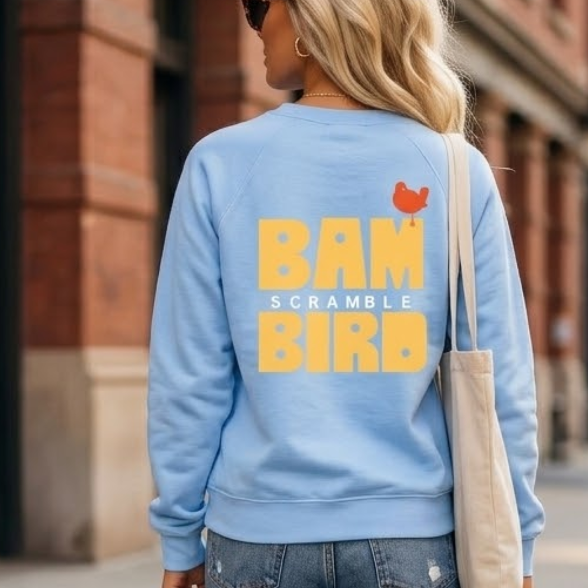 Back of the Carolina Blue Bambird Scramble crewneck showing the gold BAMBIRD SCRAMBLE print with the orange bird